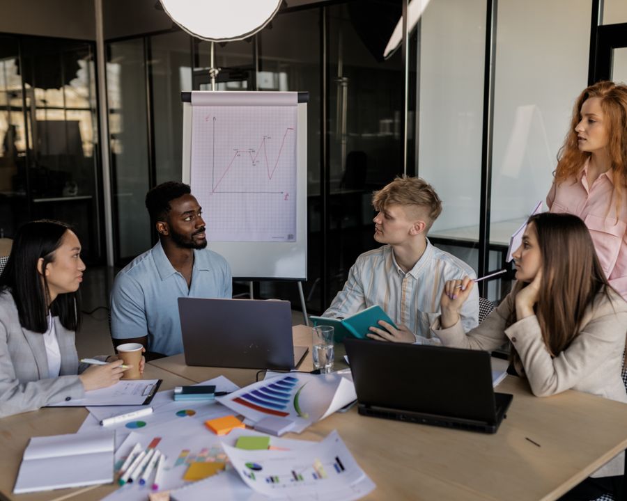 A small team around a table reviewing performance charts on a laptop